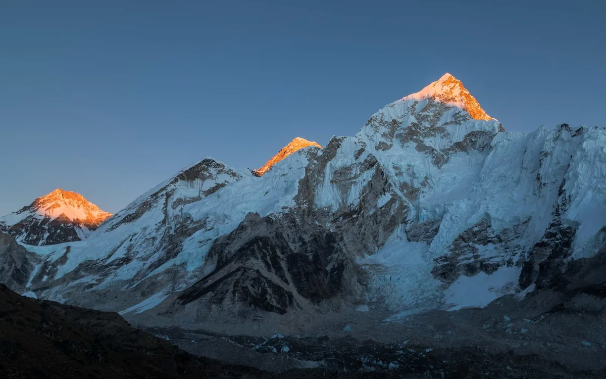 Mount Everest lit gold at sunrise, seen from a mountain flight