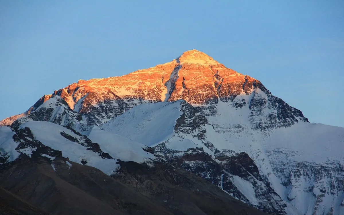 A Himalayan peak lit gold at sunrise from a mountain flight