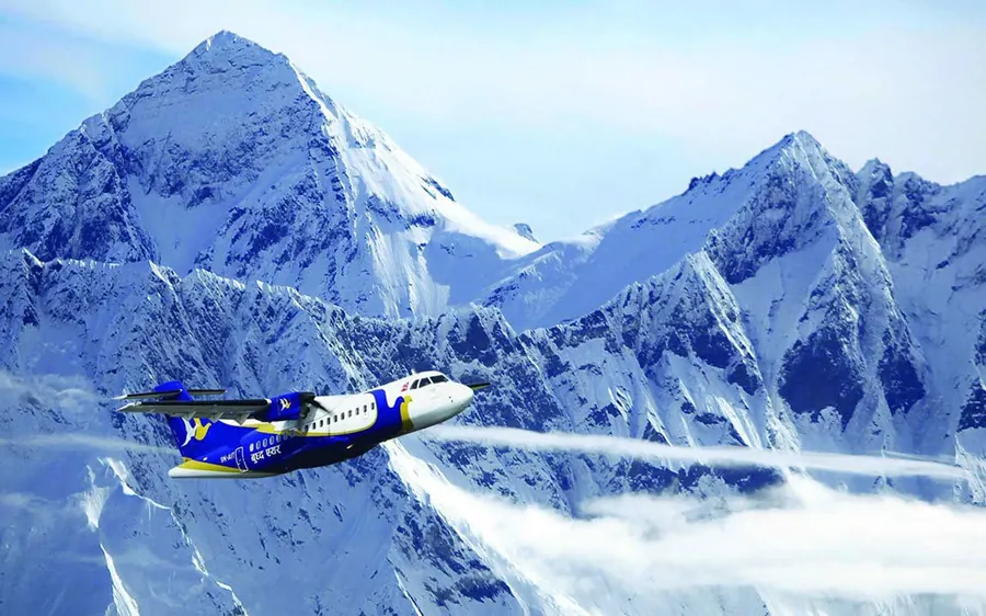 A mountain flight aircraft turning in front of a snow peak